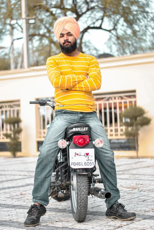 Free Indian man with turban sitting confidently on a motorcycle outdoors in Punjab, India. Stock Photo