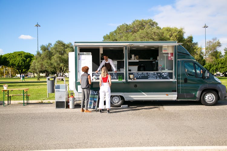 Couple Standing Near Food Truck And Choosing Food