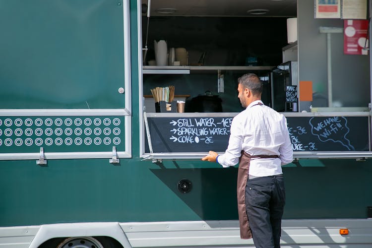 Man In Uniform Opening Counter Of Food Truck