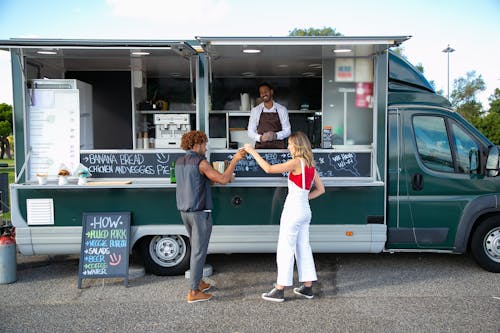 Diverse couple clinking beer at counter of food trailer
