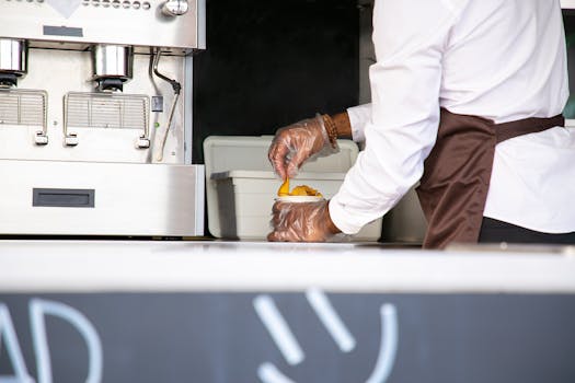 A street food vendor in uniform serving a freshly prepared meal from a truck.