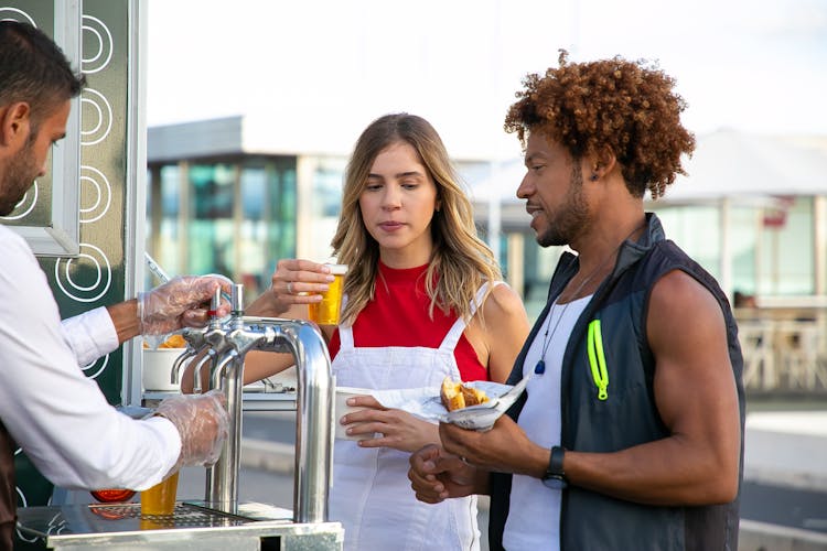 Seller Pouring Beer To Diverse Couple