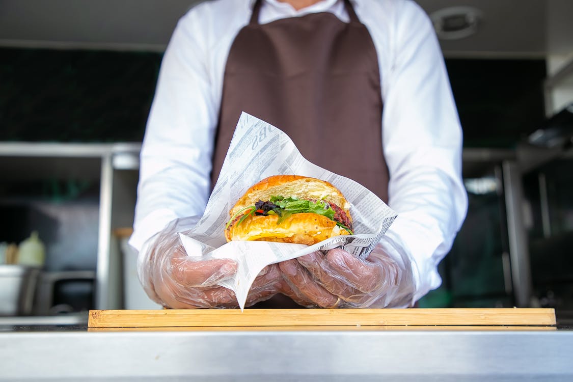Free Cook standing in food truck and giving burger Stock Photo