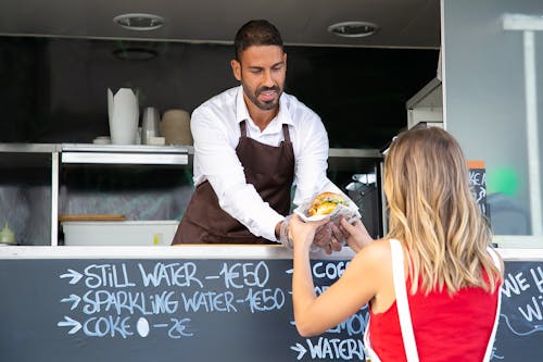 Vrouw Smakelijke Hamburger In Food Truck Kopen