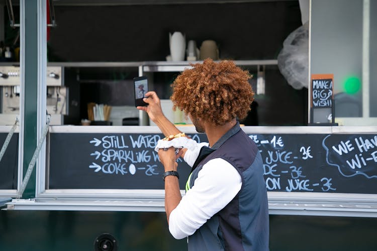 Black Faceless Man With Burger Taking Selfie Near Food Truck