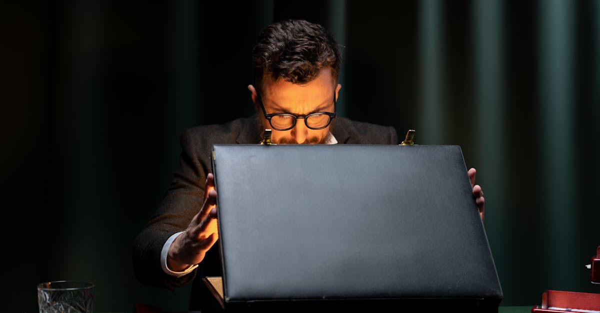 A man in a black suit is intriguingly opening a briefcase in a dimly lit room.
