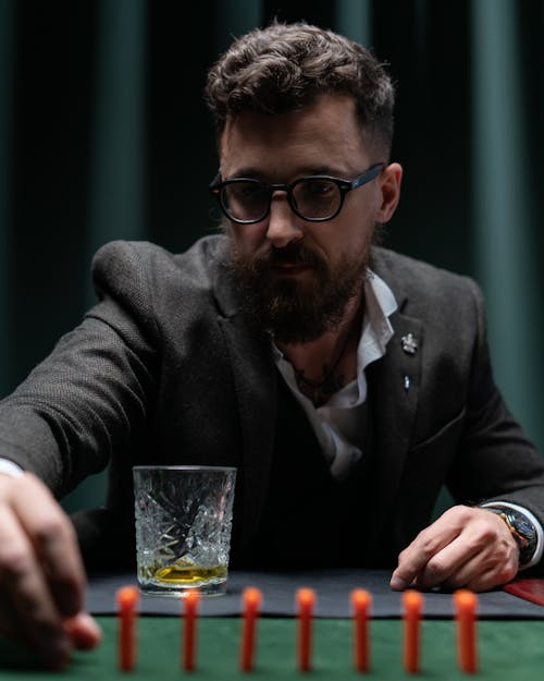 A Man in a Suit Placing Domino Tiles on a Table 