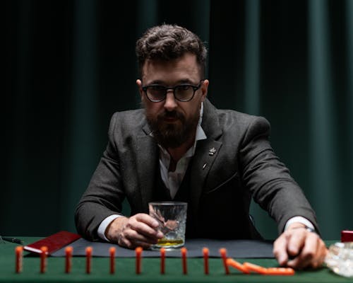 A Man in a Suit Sitting at his Desk Playing with Domino Tiles