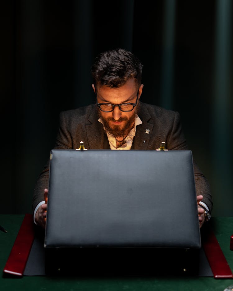 A Bearded Man In A Suit Looking Inside An Open Briefcase