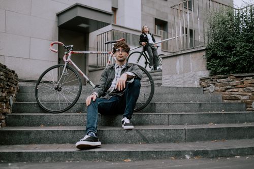 Free Two men with bicycles on city steps, showcasing urban cycling lifestyle. Stock Photo