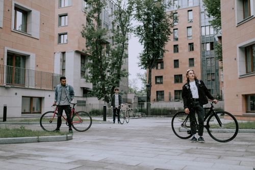 Free Three men posing with bicycles in an urban residential area, showcasing diversity and modern city living. Stock Photo