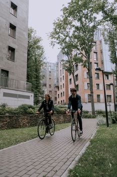 两个朋友在城市环境中骑着自行车，周围环绕着现代公寓，享受着户外休闲活动