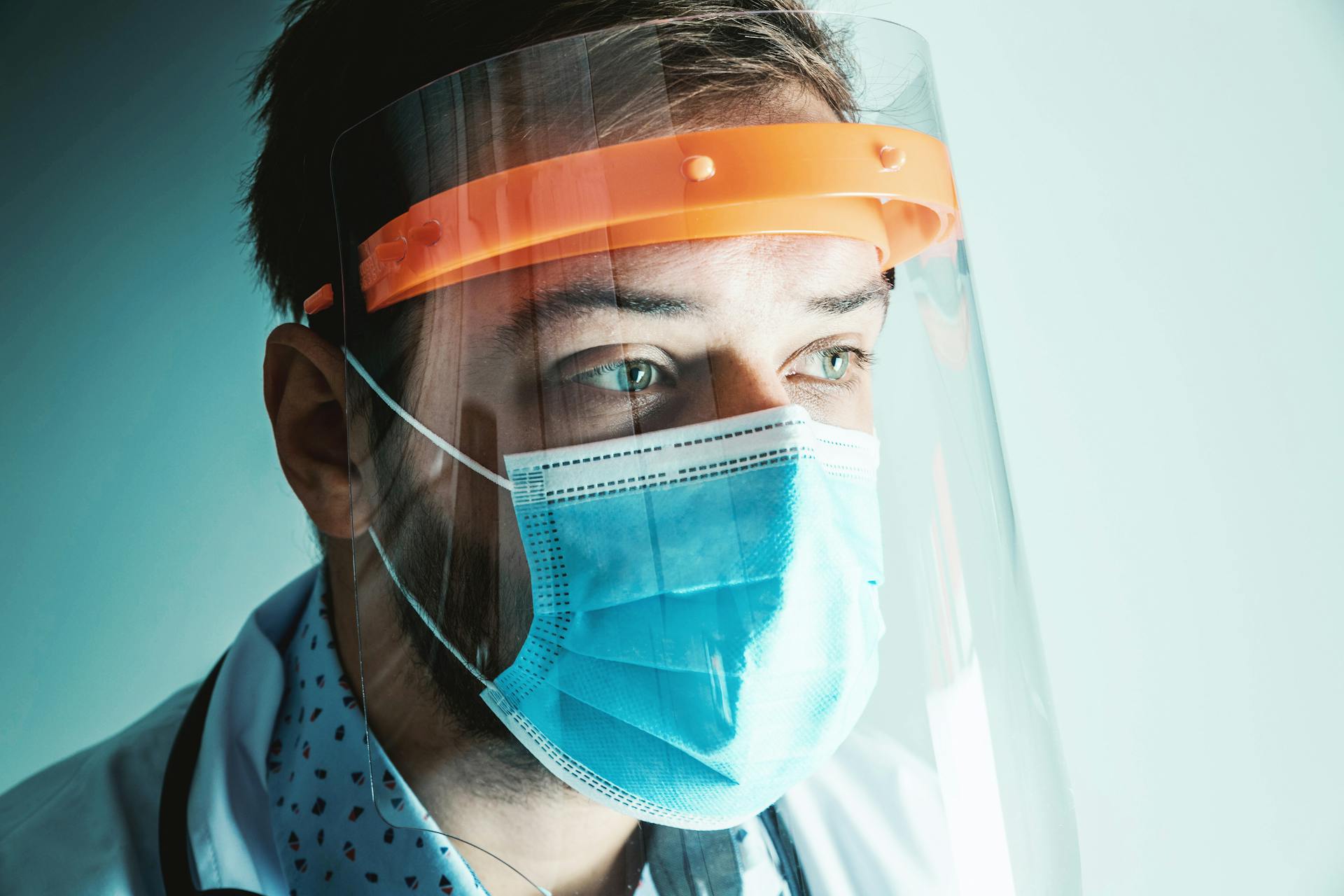 Close-up of a healthcare professional wearing personal protective equipment including a face mask and shield.