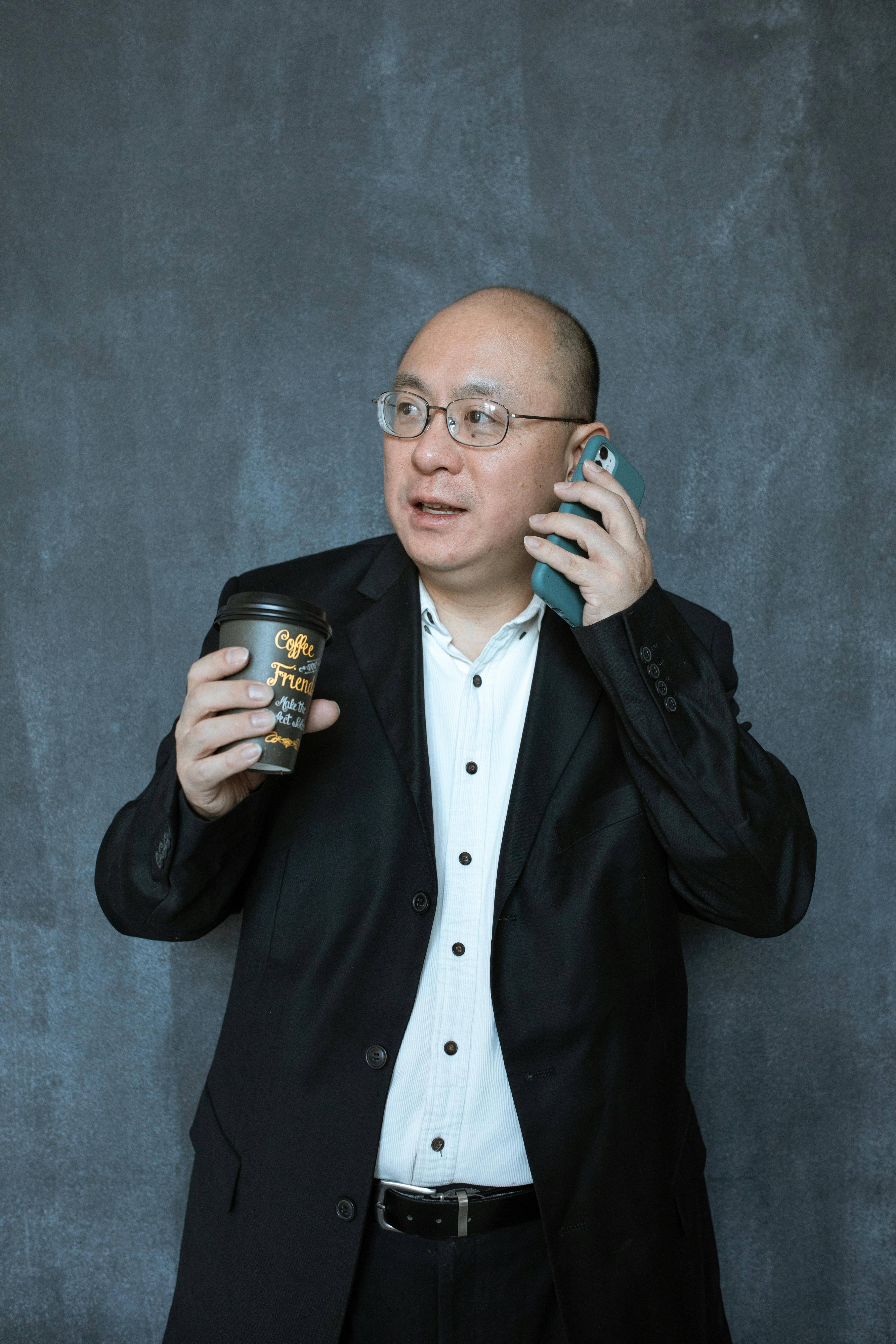 man in black suit holding black ceramic mug