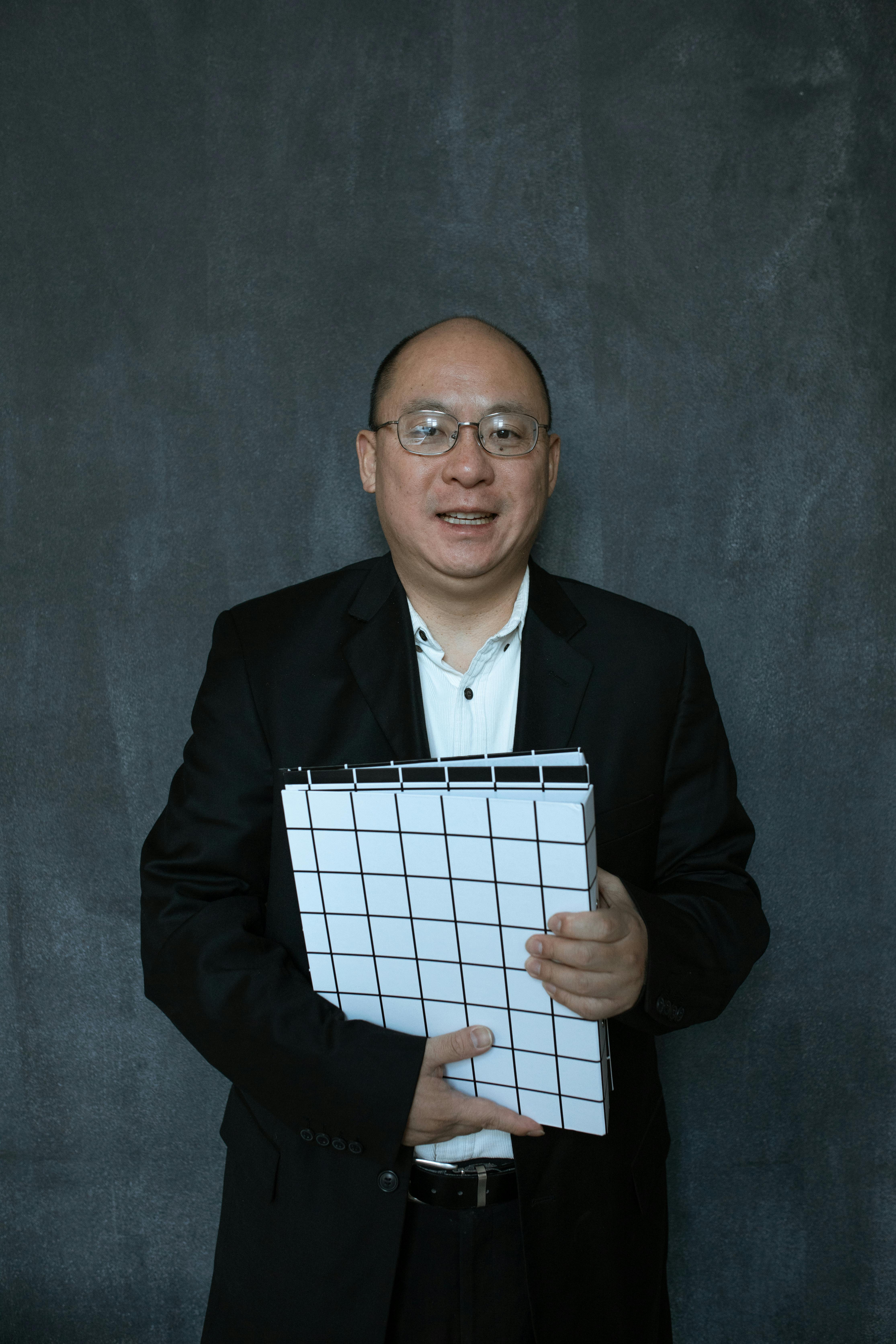 man in black suit jacket holding white and black checkered box