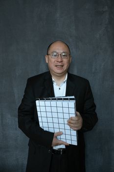 在黑暗背景下，一个穿着西装的男人自信地拿着文件夹