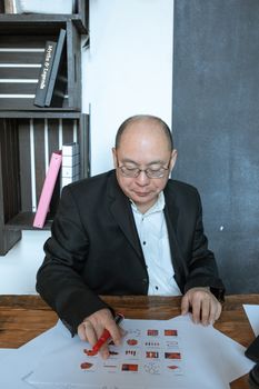 一位穿着西装的专业商人正专注地在办公桌前查看图表