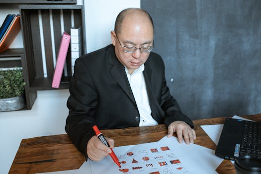 Asian businessman reviewing documents and data in a modern workspace.