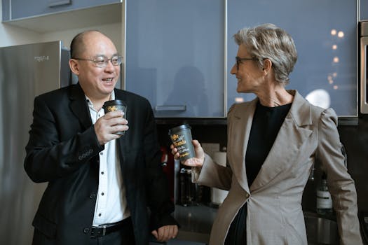 Two business professionals sharing a coffee break in a modern office kitchen.