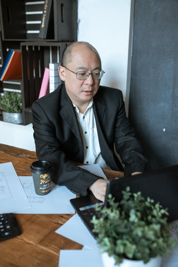 A Businessman Sitting At His Desk Using A Laptop