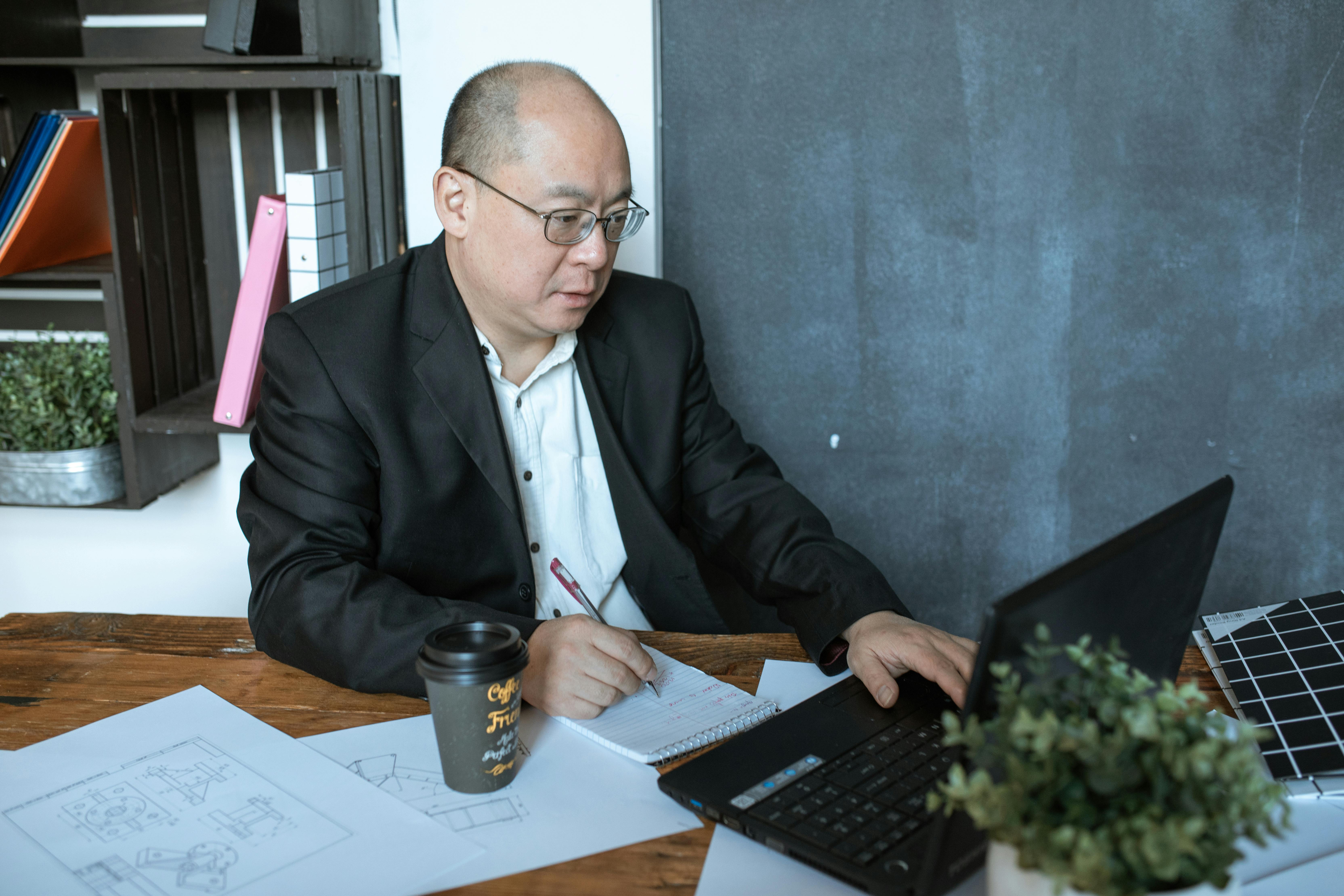 man in black suit jacket using black laptop computer