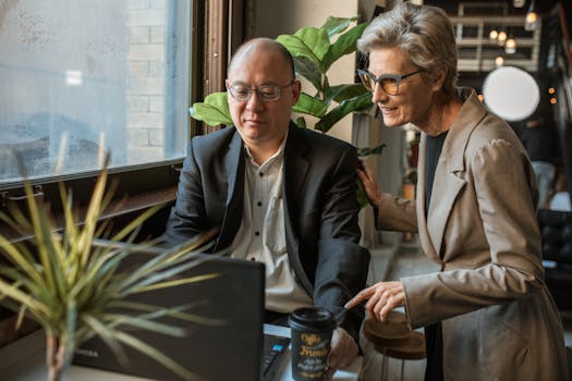 在现代办公环境中，两位同事一起使用笔记本电脑，促进团队合作与协作