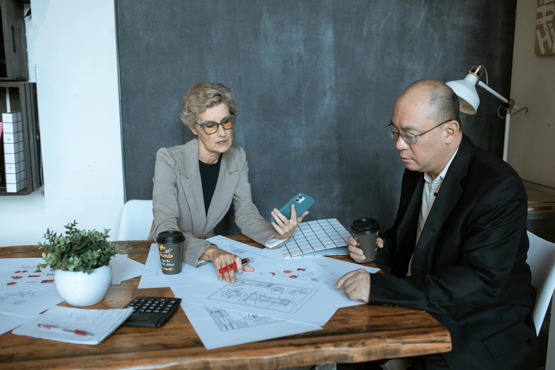 Two business professionals discuss project designs at an office desk.