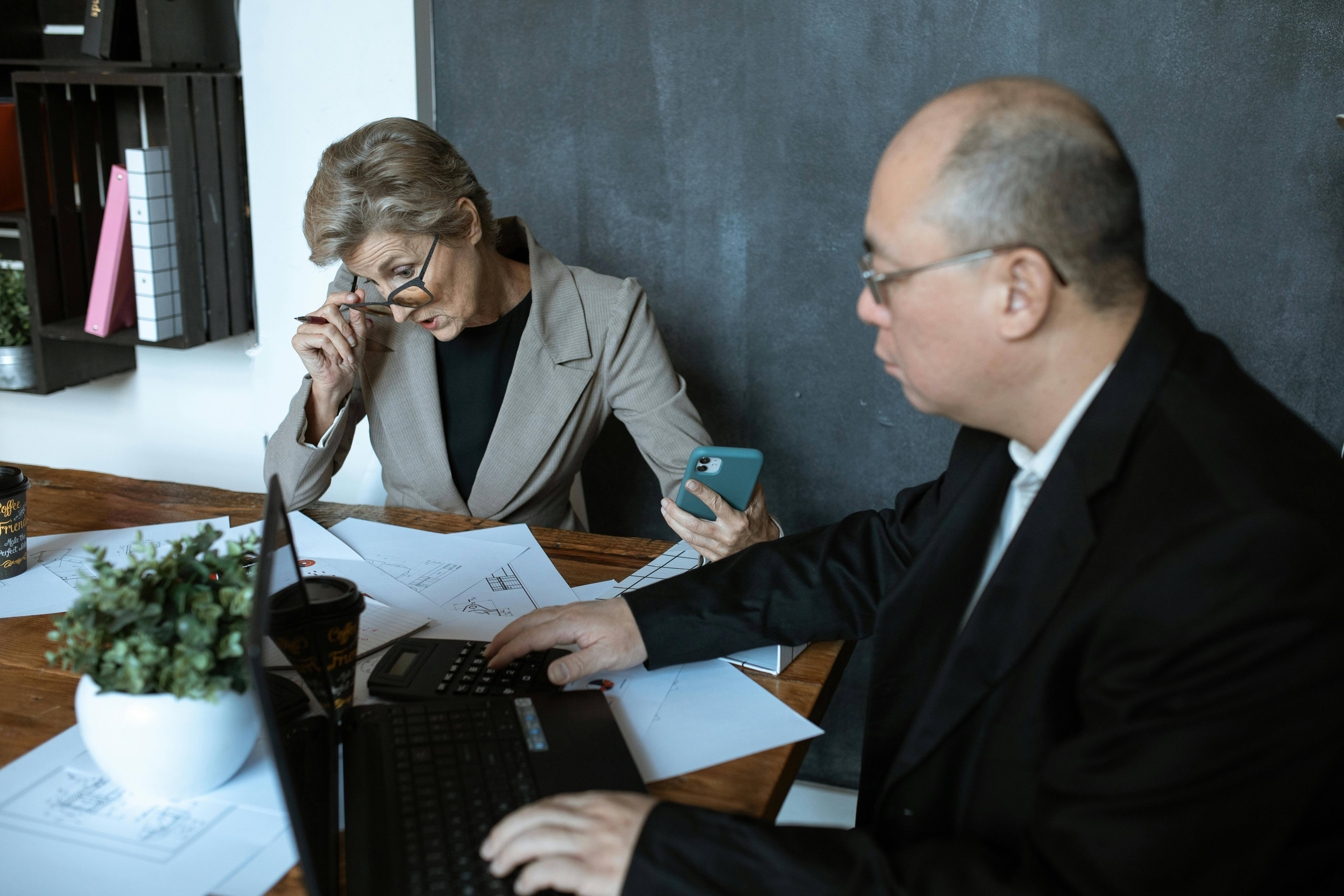 man in black suit jacket holding black laptop computer