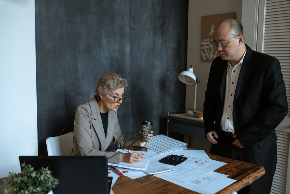 Profesionales senior colaboran en un entorno de oficina moderno. Incluye documentos y discusiones.