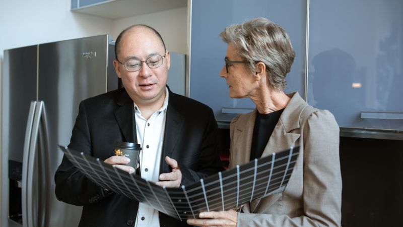 couple comparing stainless steel refrigerators in an appliance showroom
