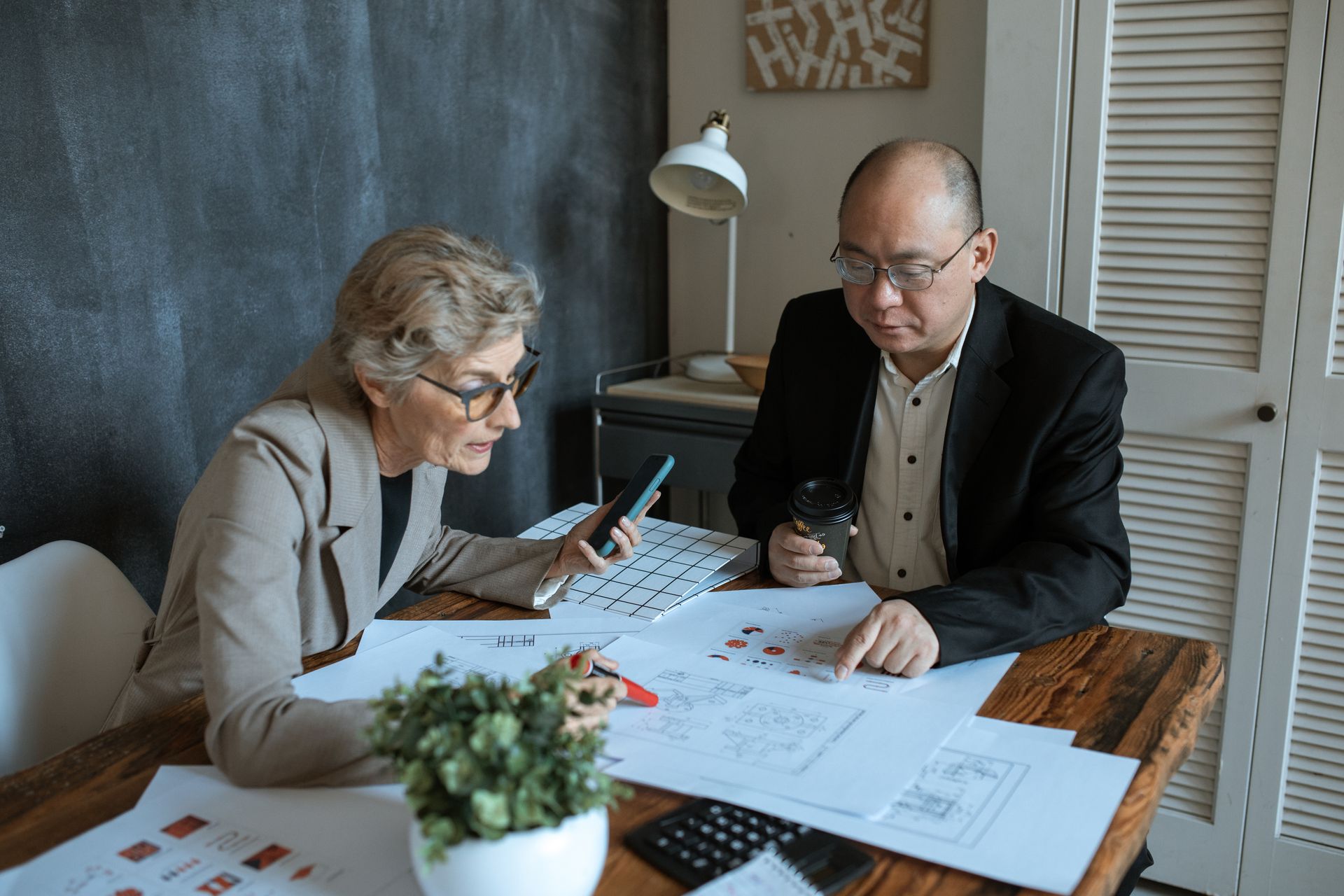 Diverse team of professionals working on project plans at a desk. Collaborative business environment.