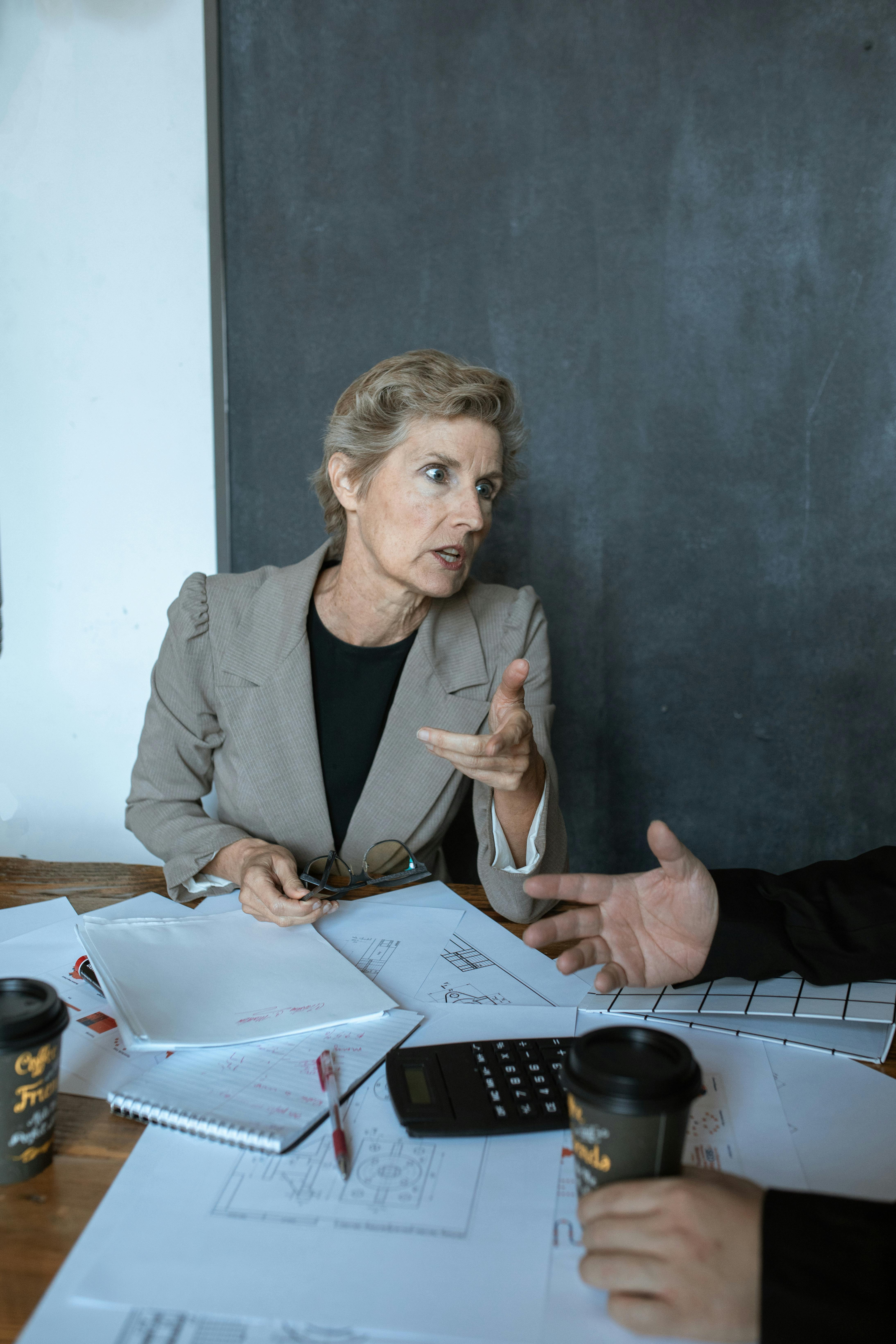 woman in gray blazer holding white printer paper