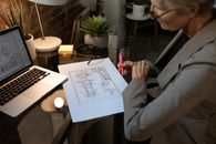在现代工作空间中，高级女性使用笔记本电脑分析建筑计划
