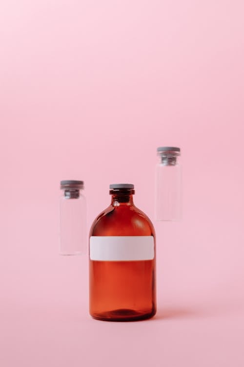 Three Small Glass Bottles on Pink Surface