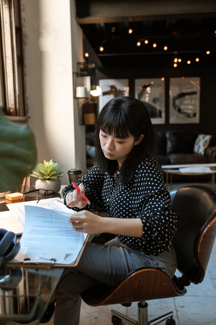 Woman Sitting On Office Chair Reading Documents