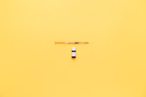 Free Vial And Syringe On Yellow Surface Stock Photo