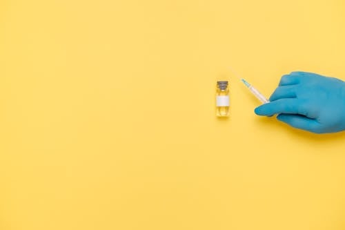 Free Person In Blue Gloves Holding A Syringe Stock Photo