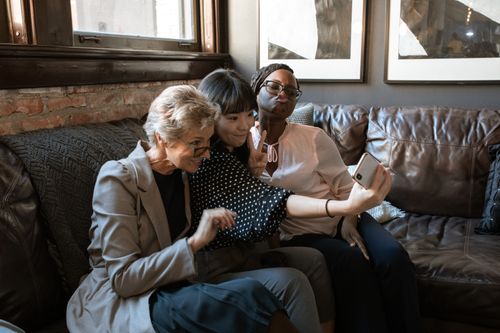 Free A group of diverse friends enjoying a selfie together on a cozy couch in a stylish interior. Stock Photo