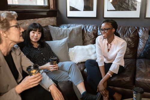Free Three women in a cozy setting having a casual conversation with coffee. Stock Photo