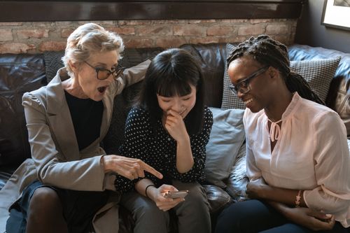 Free Three women of different ethnicities sharing a light-hearted moment indoors. Stock Photo