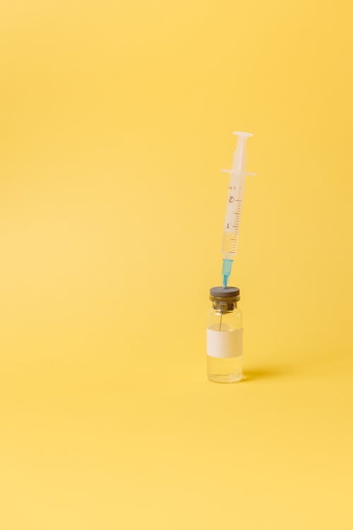 Free Syringe And A Vial On Yellow Surface Stock Photo