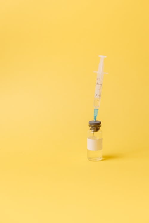 Syringe And A Vial On Yellow Surface