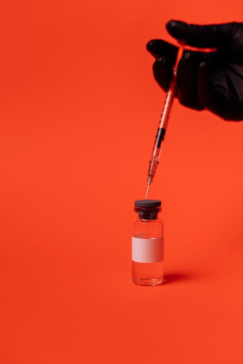 Free Person Wearing Black Gloves Holding a Syringe Stock Photo