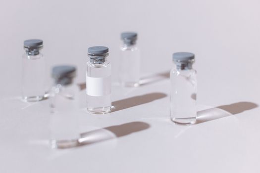 透明玻璃小瓶用于疫苗或药物，展示在无菌白色表面上