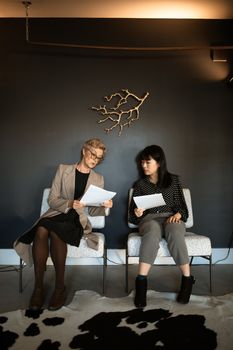 两名妇女在办公室里审查商业文件，体现了团队合作的重要性