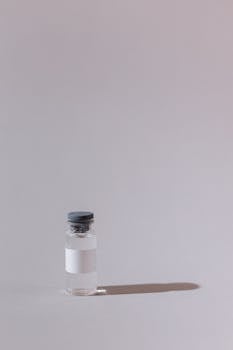 A single glass vial with a cork stopper against a gray backdrop, casting a shadow.