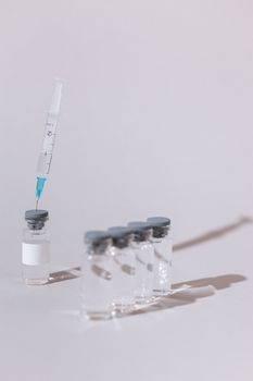 将注射器置于白色表面的玻璃疫苗小瓶上，注射器内含有透明物质