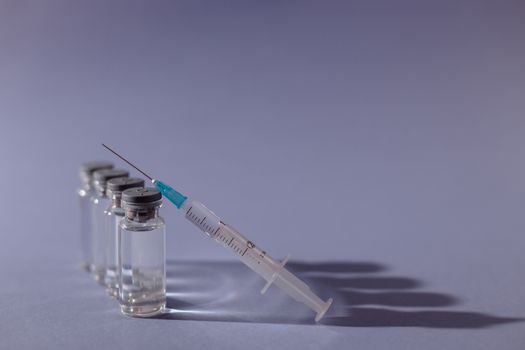 灰色表面上排列着注射器和疫苗小瓶，象征着医疗保健和预防接种