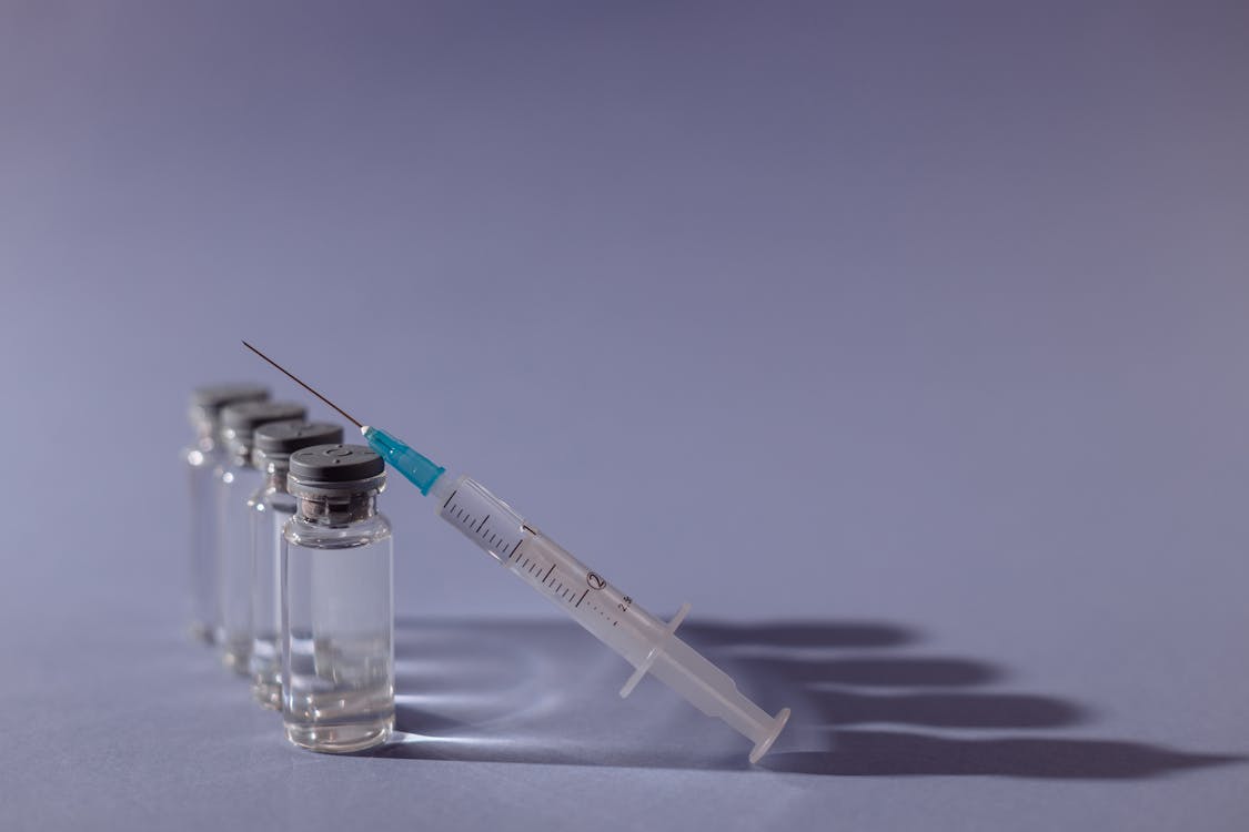 Free Syringe and vaccine vials arranged on gray surface, symbolizing healthcare and immunization. Stock Photo