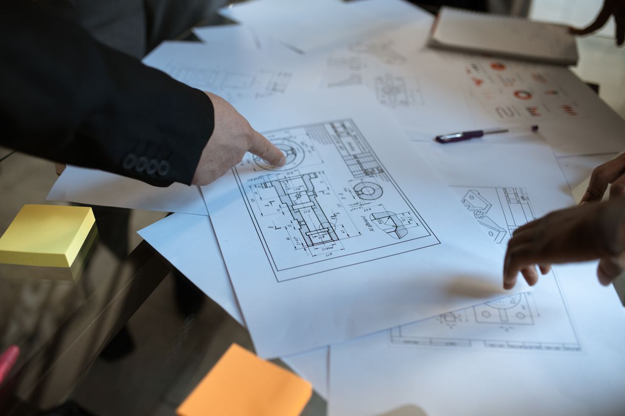 Engineers discussing blueprints at a workspace, focusing on teamwork and architecture design